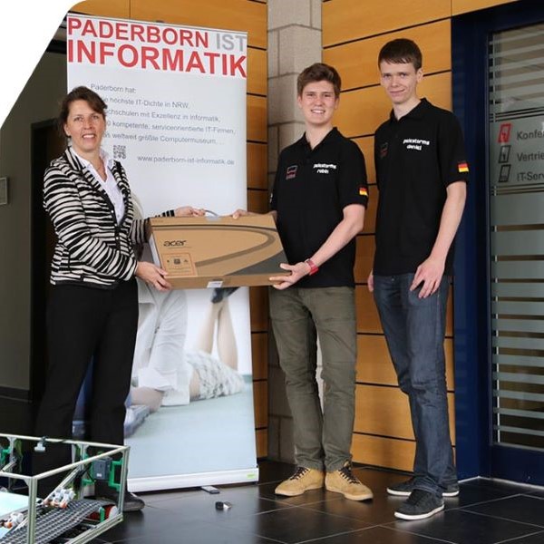 Dr. Elke Radeke überreicht dem Roboterteam einen hochwertigen Laptop für die Meisterschaft in Jakarta (zwei Schüler der Pelestorms: Robin Drabon und Daniel Häger) Dr. Elke Radeke und das Paderborner Roboterteam